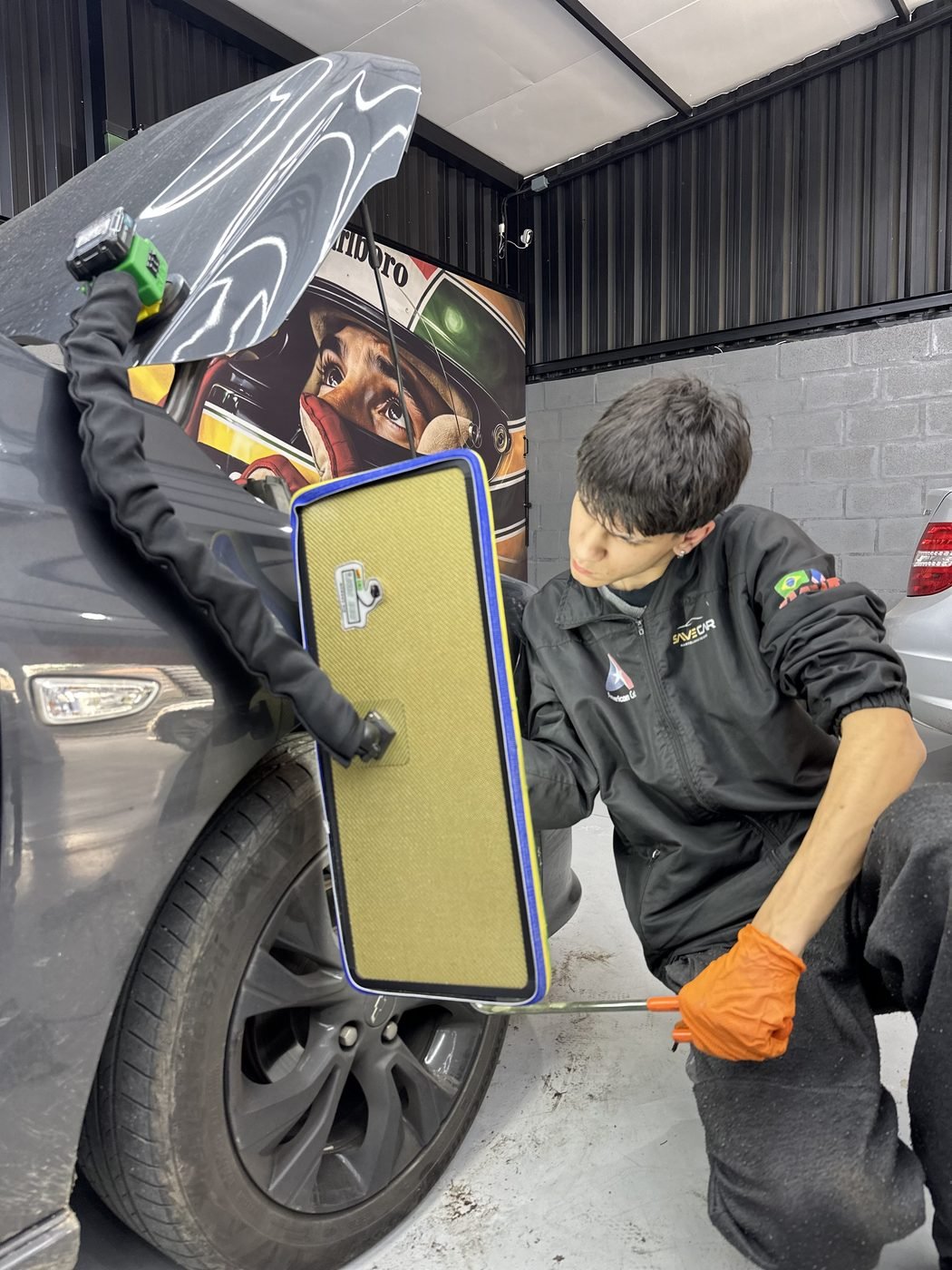 Técnico realizando martelinho de ouro em amassado de veículo
